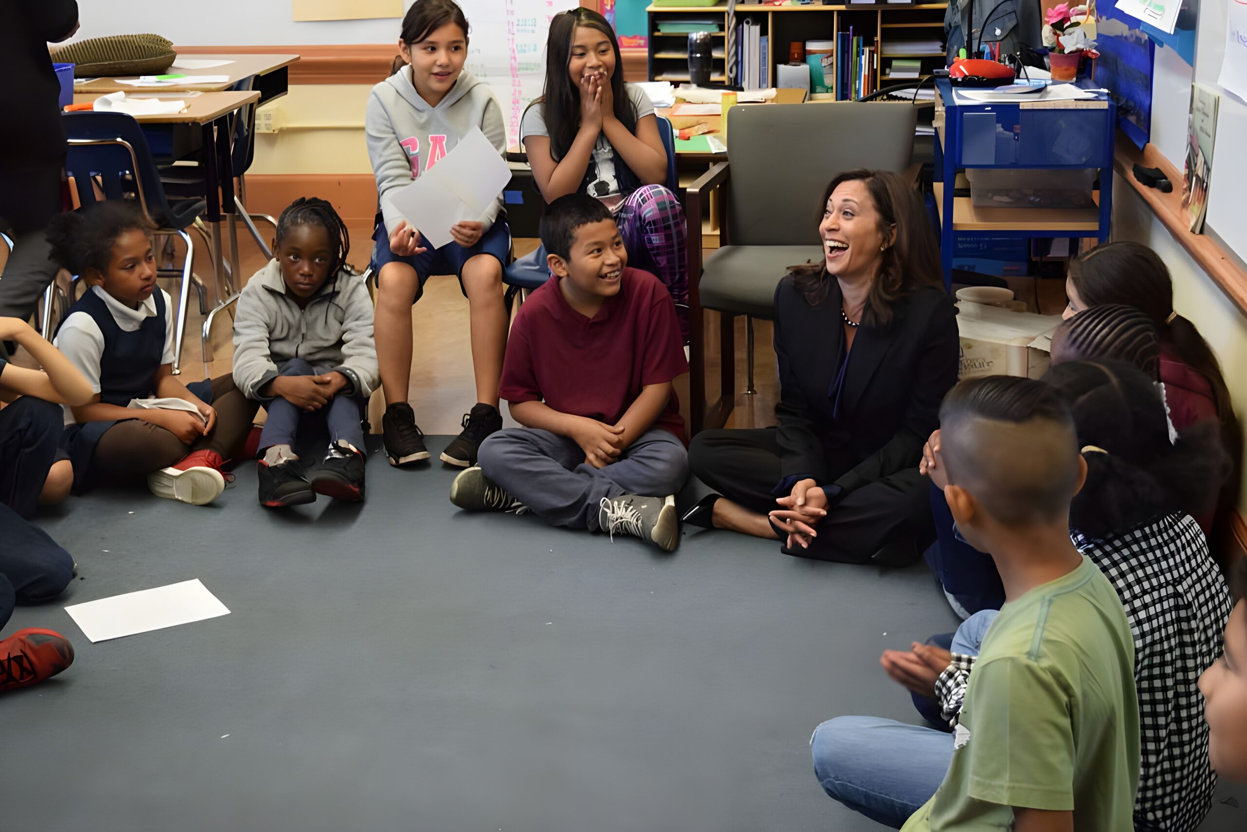 Attorney General Kamala Harris sitting on the floor in a classroom, surrounded by children.